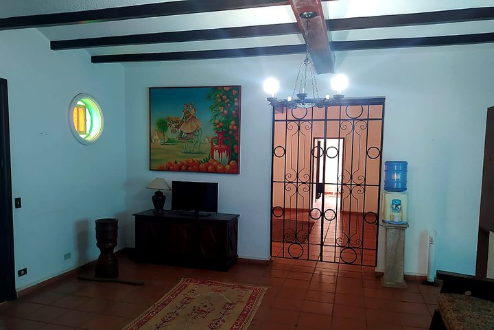 Sala da unidade com televisão, mobiliário de madeira e acesso ao corredor