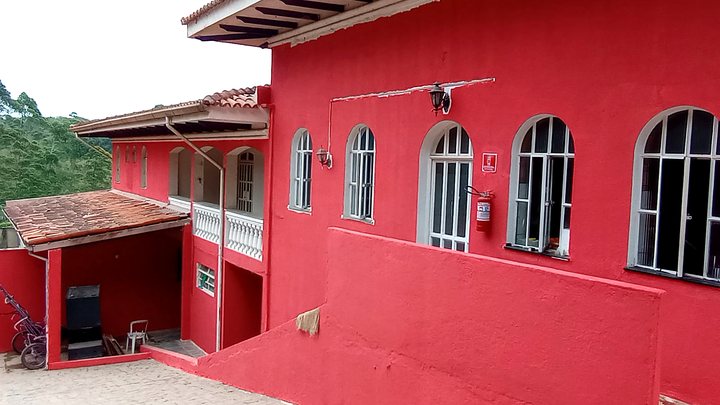 Fachada vermelha com janelas brancas e varandas da unidade