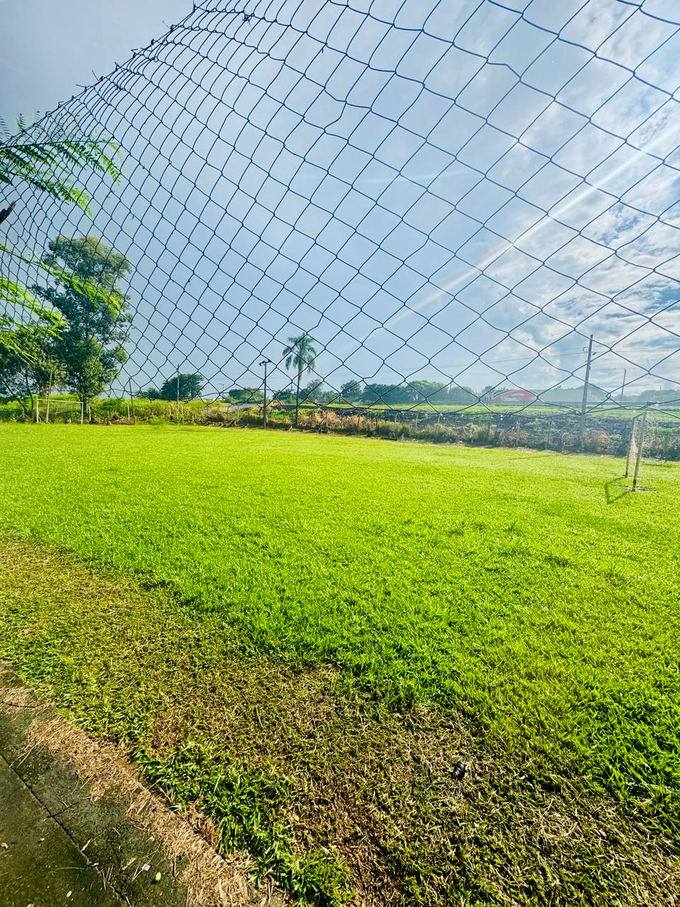 Campo de grama com traves, cercado por tela